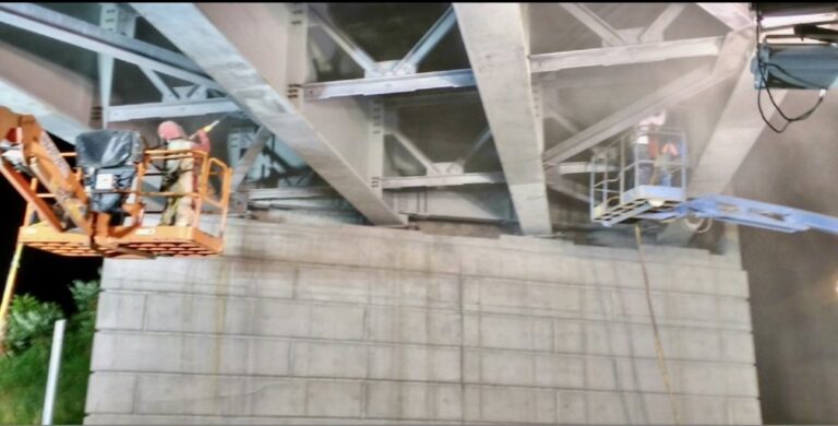 Sablage au jet sous un viaduc après un incendie